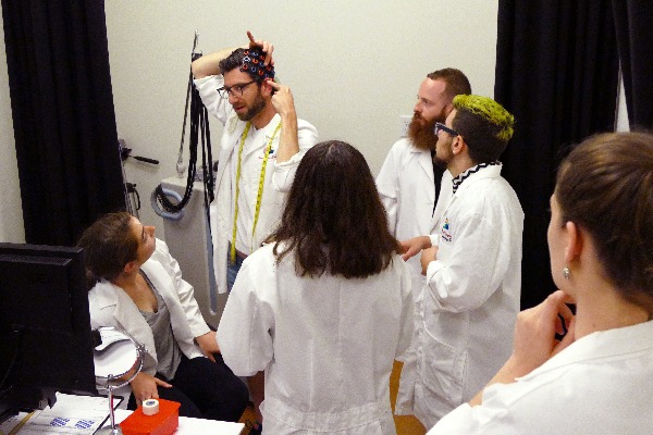 a man with white lab coat showing how the technology on head work to the students with white lab coat.