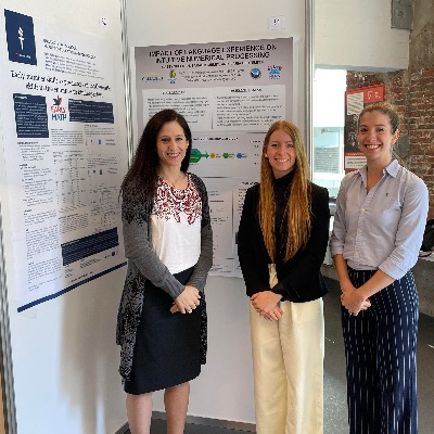 Three women are standing in front of two academic posters.