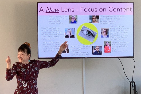 Dr. Laura-Ann Petitto points at her presentation and points at a person in the audience at the same time.