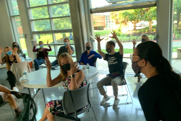 VL2 members, with their masks on, handwave at a student.