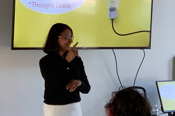 Poorna signs with yellow-background presentation behind her.