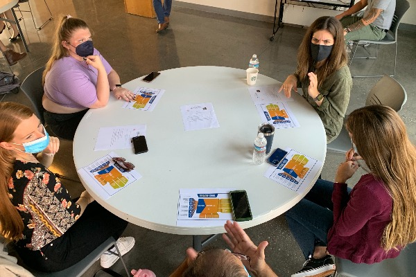 Students sit around a white rounded table and discusses