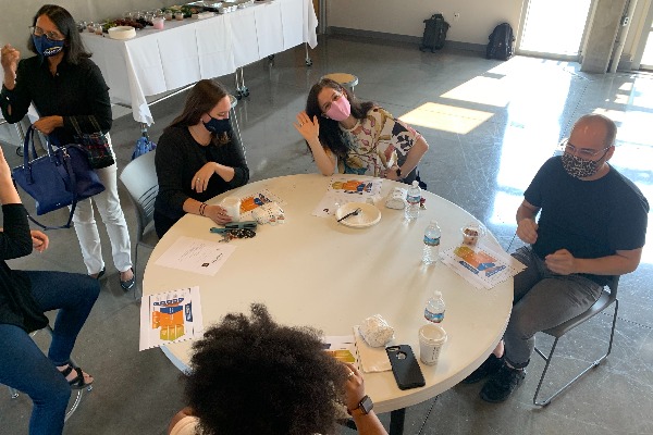 Faculty and students sit around a white rounded table.