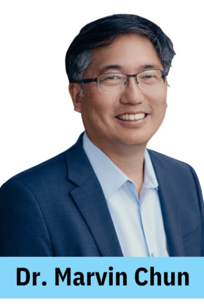 ID: A asian-presenting man with short black and grey hair and thin rectangular glasses is smiling. 